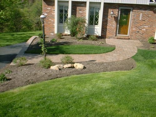 Exterior of brick home with curved walkway and manicured lawn.