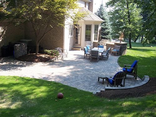 Backyard patio with dining set, seating area, and lush green lawn.