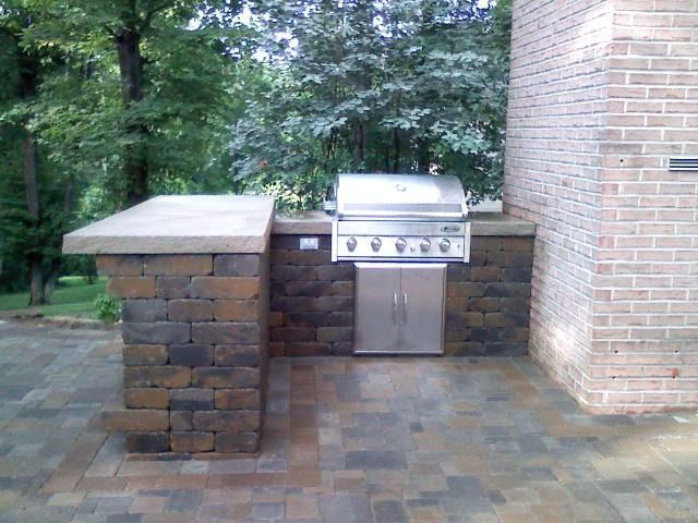 Outdoor brick grill station with stainless steel grill, counter, and brick patio.