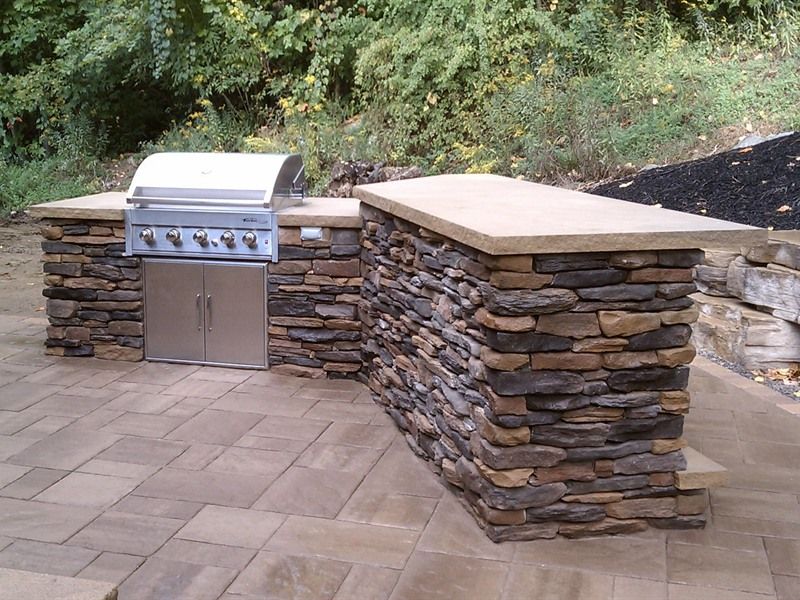 Outdoor stone kitchen with grill and countertop.