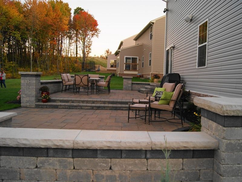 Patio with seating, brick retaining walls, and fall foliage in a backyard setting.