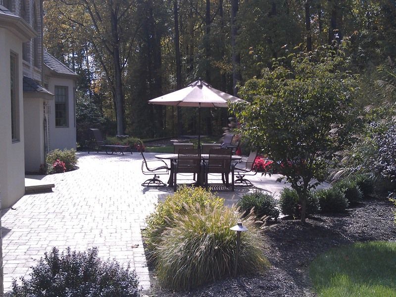 Patio with brick pavers, outdoor dining set, umbrella, and landscaped garden.
