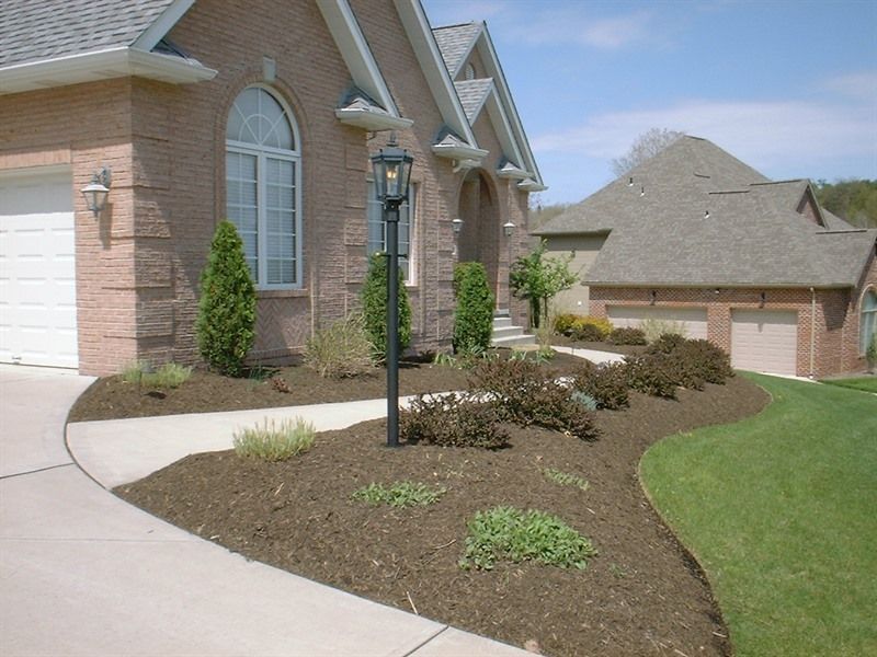 Brick house with landscaped front yard, walkway, and lamp post.