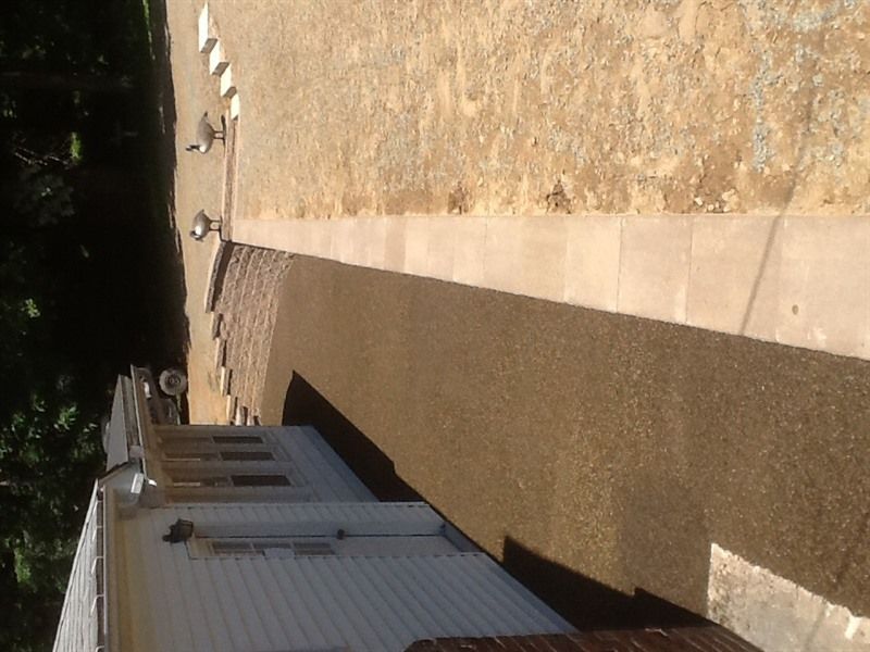Building with white siding and a gravel walkway alongside a tan surface.