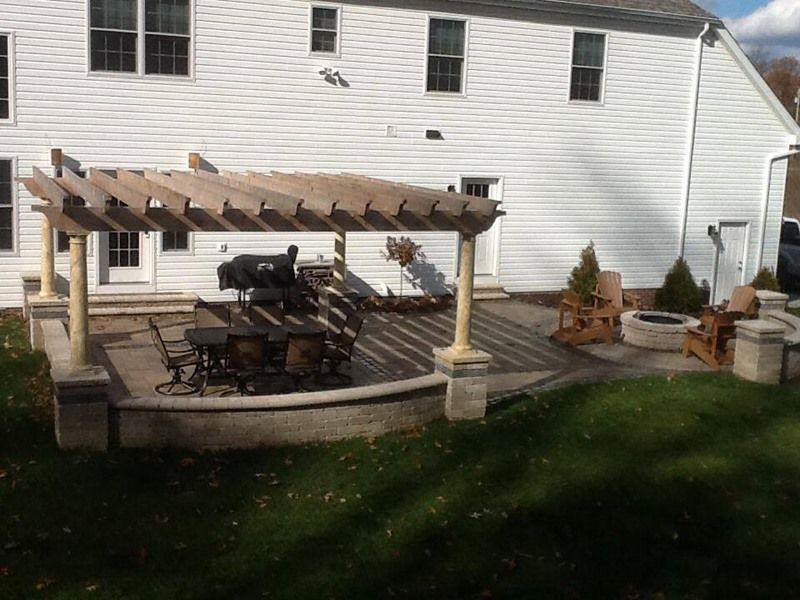 Backyard patio with pergola, grill, fire pit, and seating.