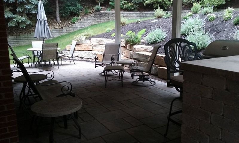 Patio with outdoor seating and built-in grill area, with a terraced hillside in the background.