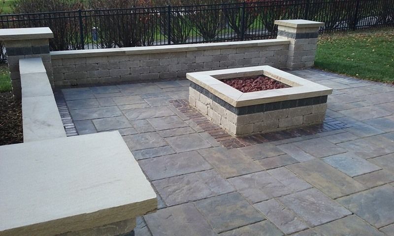 Patio with a stone fire pit and retaining wall.