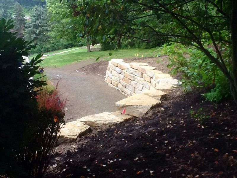 Stone retaining wall in a garden setting, with a path leading uphill.