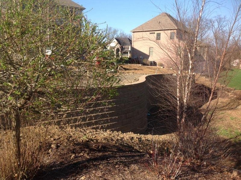 Earthen retaining wall construction near a house on a sunny day.