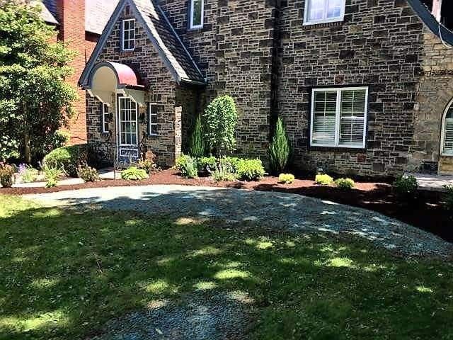 Stone house with a landscaped yard and a shade-dappled lawn.