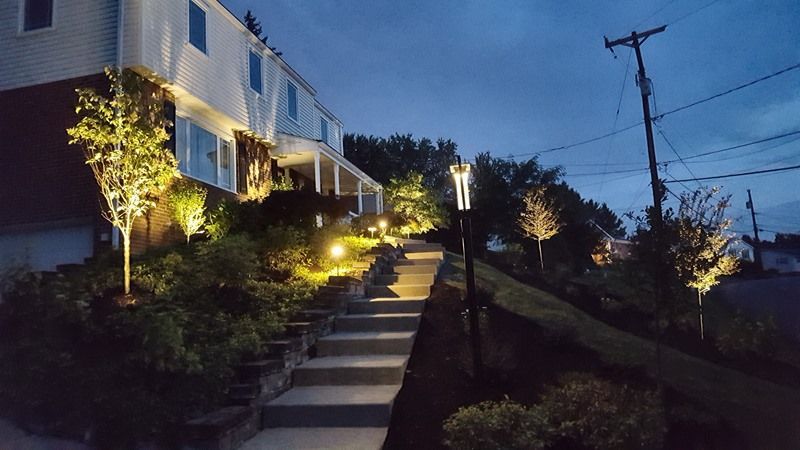 Night view of illuminated stone steps and landscaping leading to a white building.