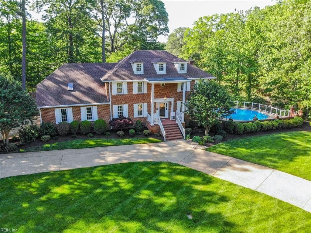 An aerial view of a large brick house with a pool in the backyard.