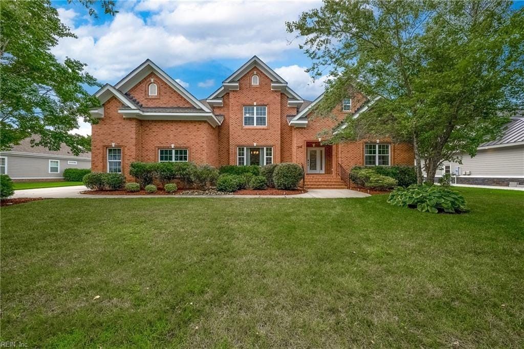 A large brick house with a large lawn in front of it.