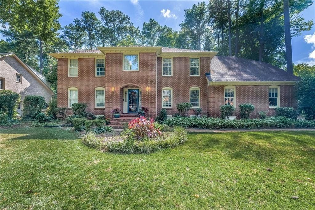 A large brick house with a lush green lawn in front of it