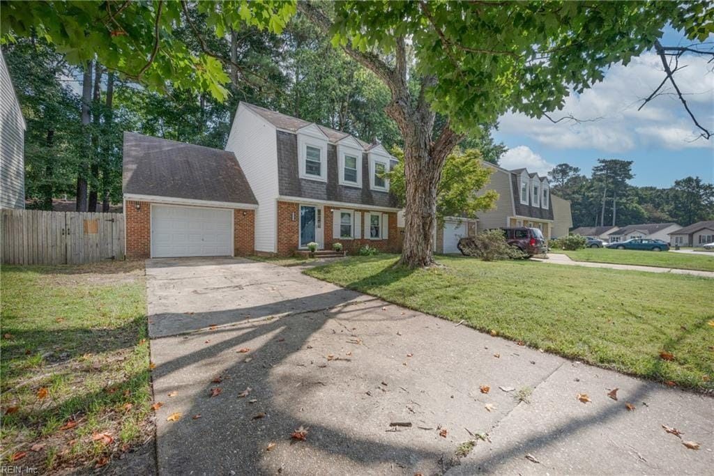 A house with a driveway and a tree in front of it.
