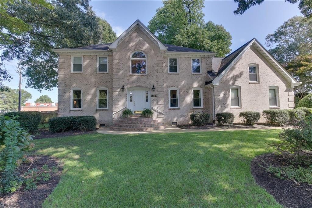 A large brick house with a large lawn in front of it