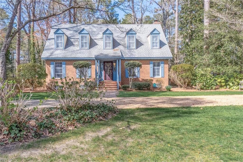 A large brick house with blue shutters is surrounded by trees and grass.