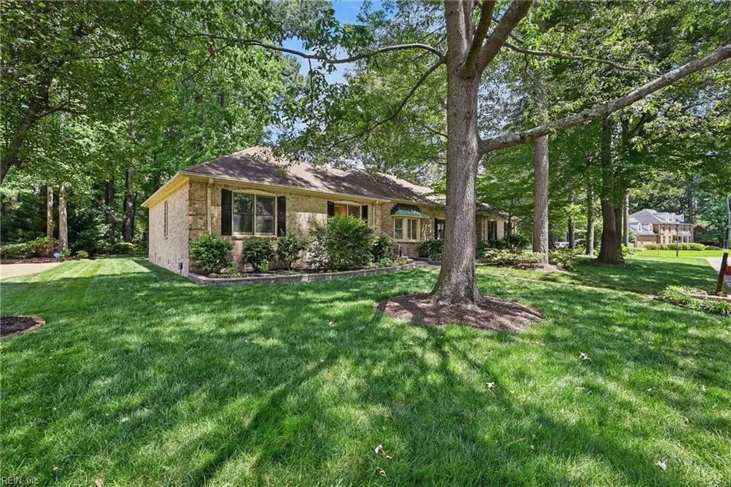 A house is sitting on top of a lush green lawn surrounded by trees.