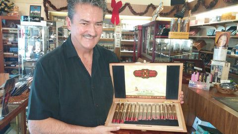 Two men are standing next to each other in a store holding boxes of cigars.