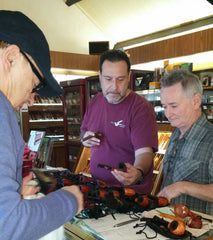 A group of men are standing around a table in a store looking at pipes.