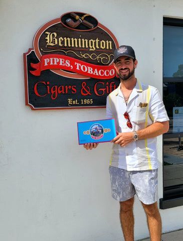A man is standing in front of a sign that says cigars and tobacco.