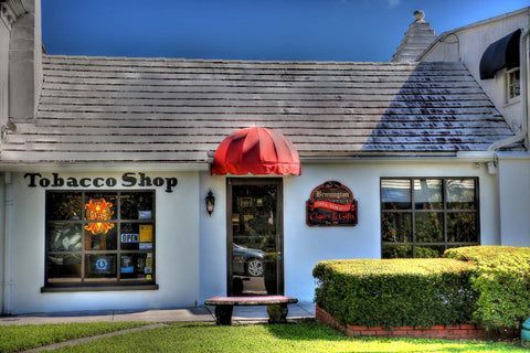 A white building with a red awning that says tobacco shop