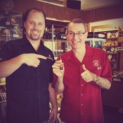 Two men are standing next to each other in a store holding a bottle of beer.