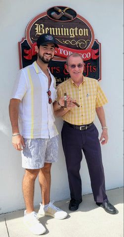 Two men are standing next to each other in front of a burlington tobacco sign.