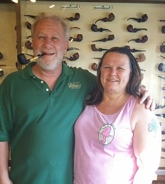 A man and a woman are posing for a picture in front of a wall of pipes.