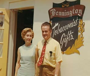 A man in a suit and tie is holding a tray of cigars