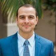 A man in a blue suit and tie is smiling for the camera.