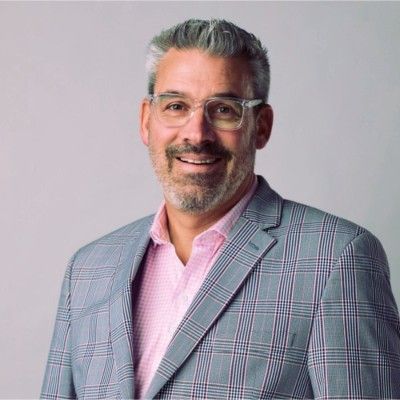 A man wearing a suit and glasses is smiling for the camera.