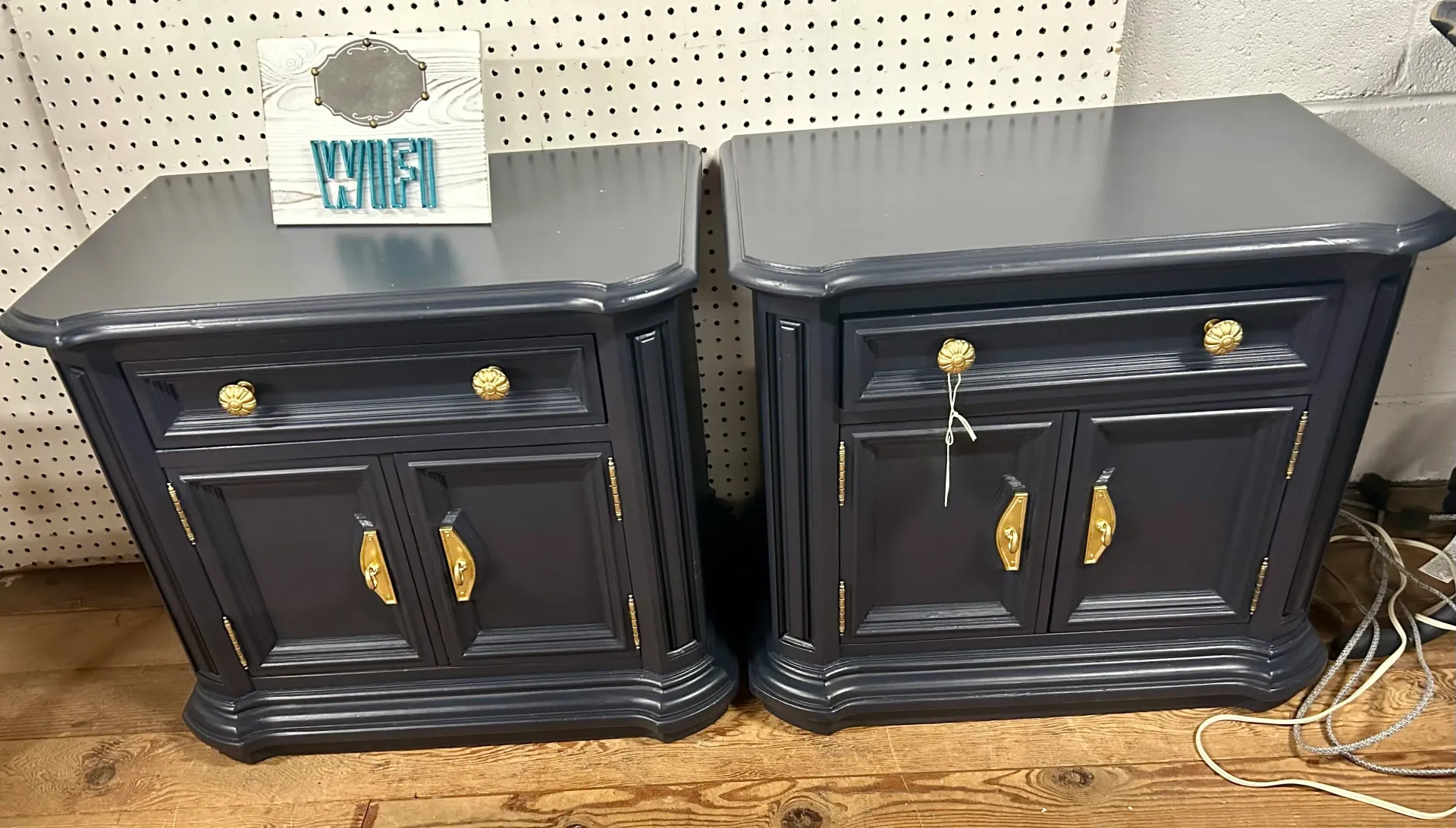 Two identical, dark blue painted wooden nightstands with gold hardware and a small white 