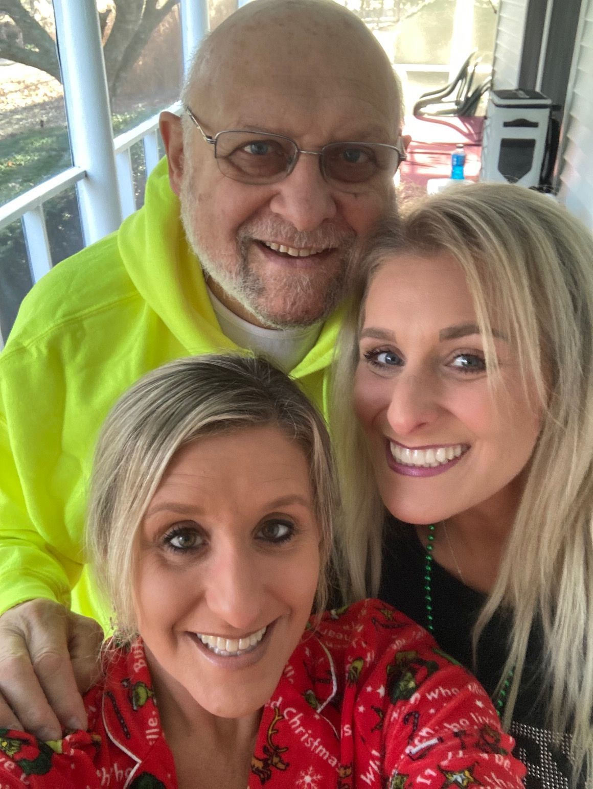 A man and two women are posing for a picture on a porch.