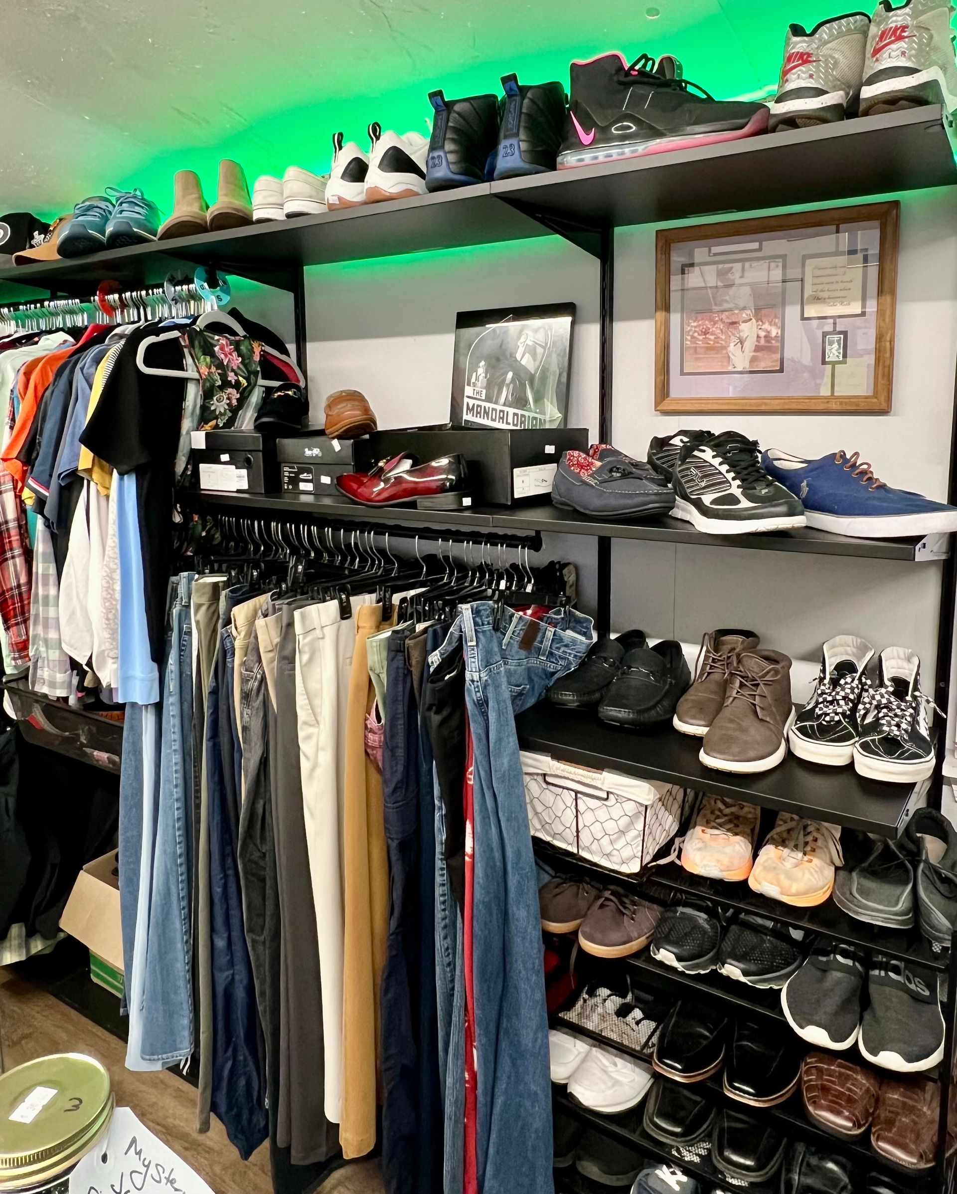 A closet area with hanging clothes and several shelves displaying multiple pairs of sneakers and shoes.