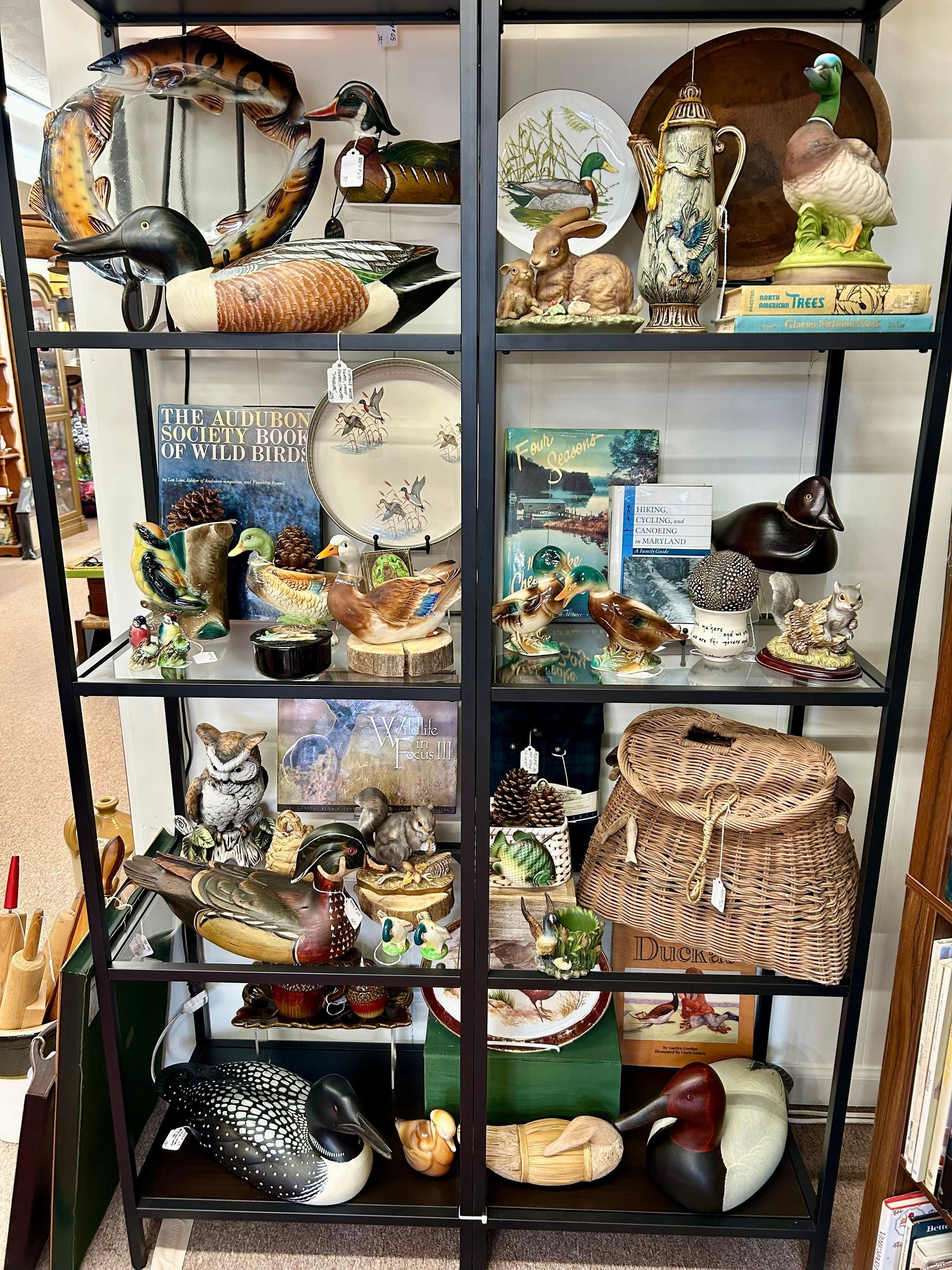 A black metal shelving unit displaying a collection of decorative bird figurines, plates, and ceramic home decor items.