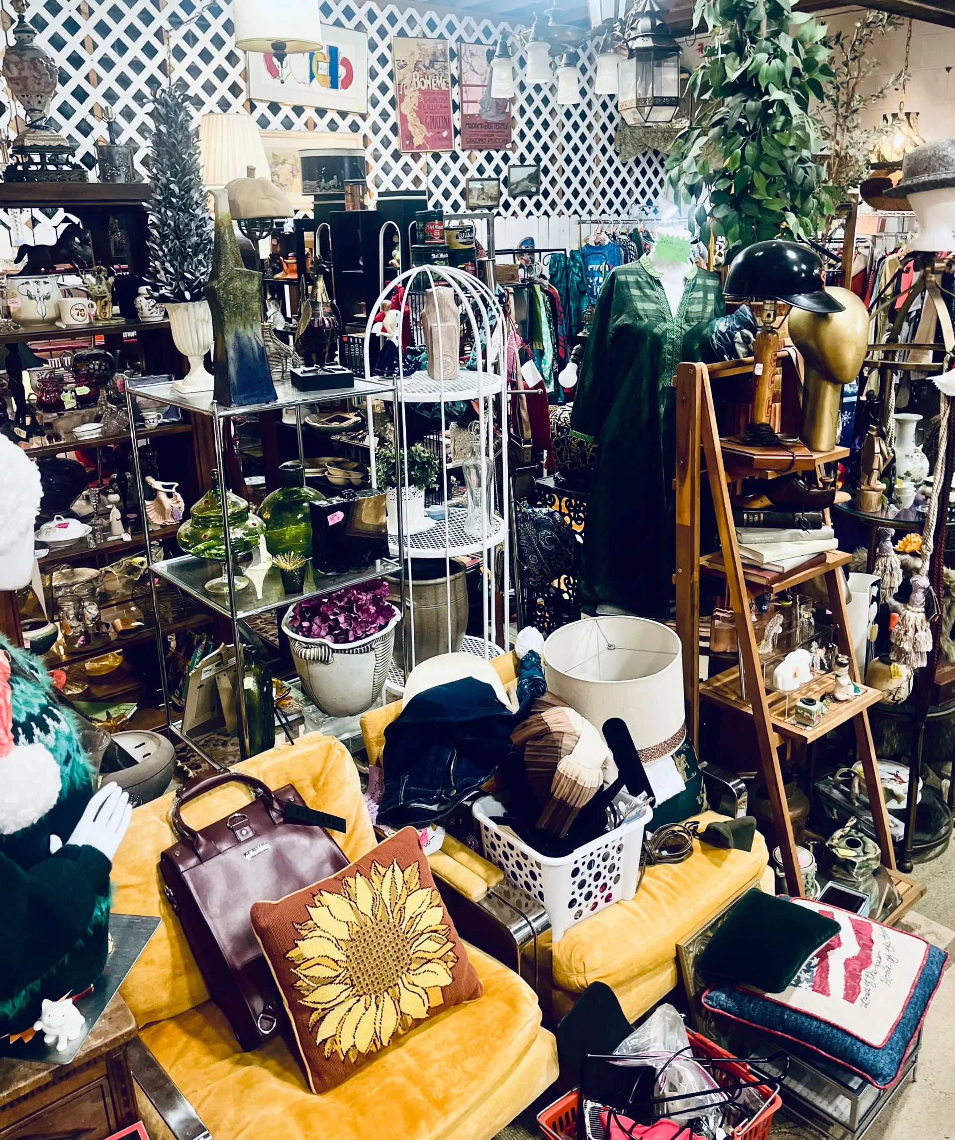 A cluttered antique store aisle featuring a yellow chair with a sunflower pillow, various knickknacks, and shelf displays.