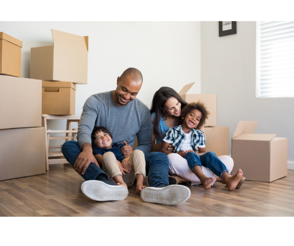 Family sitting on floor of new home with moving boxes