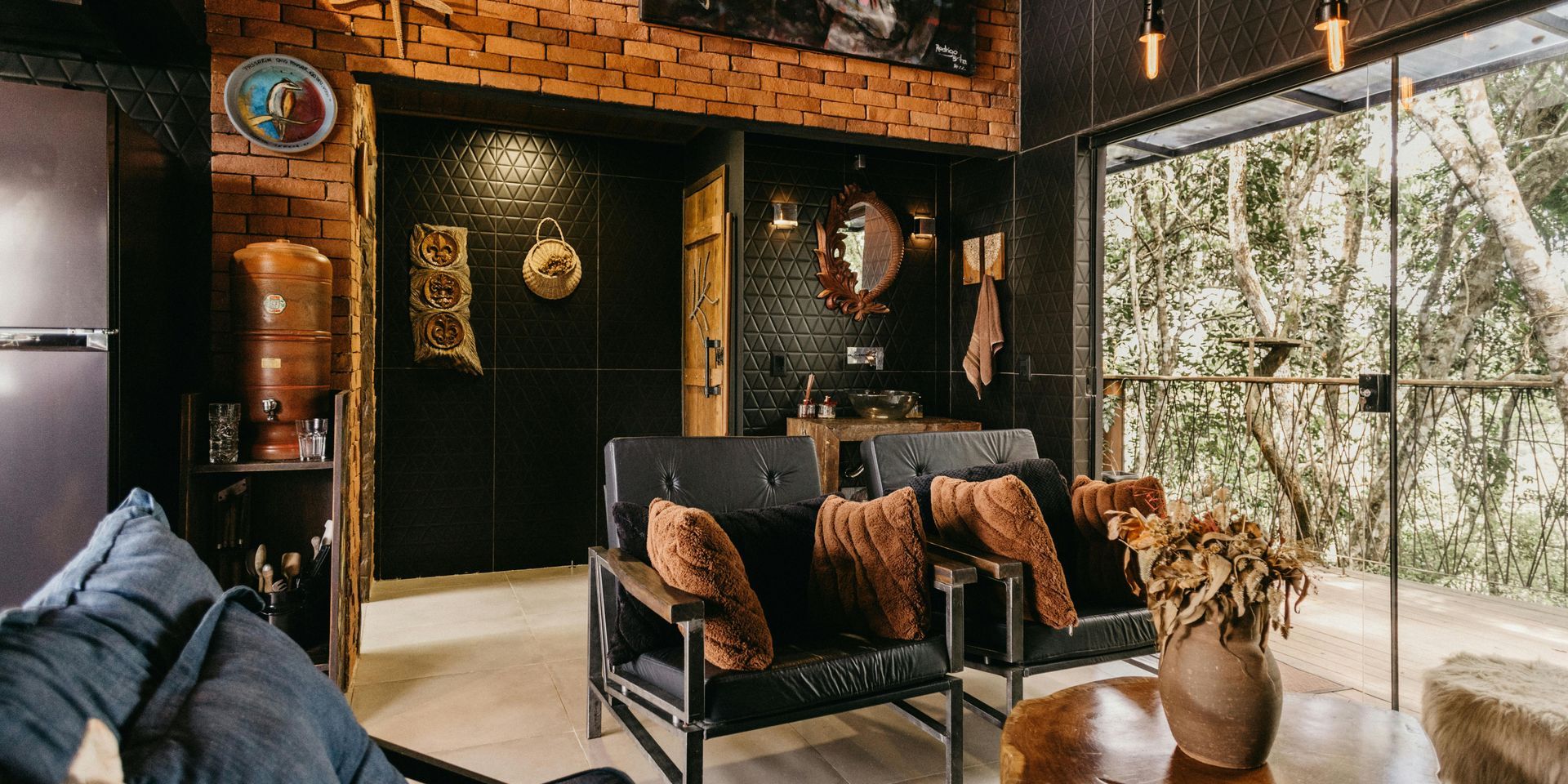 A living room with a couch , chairs , a table and a refrigerator.