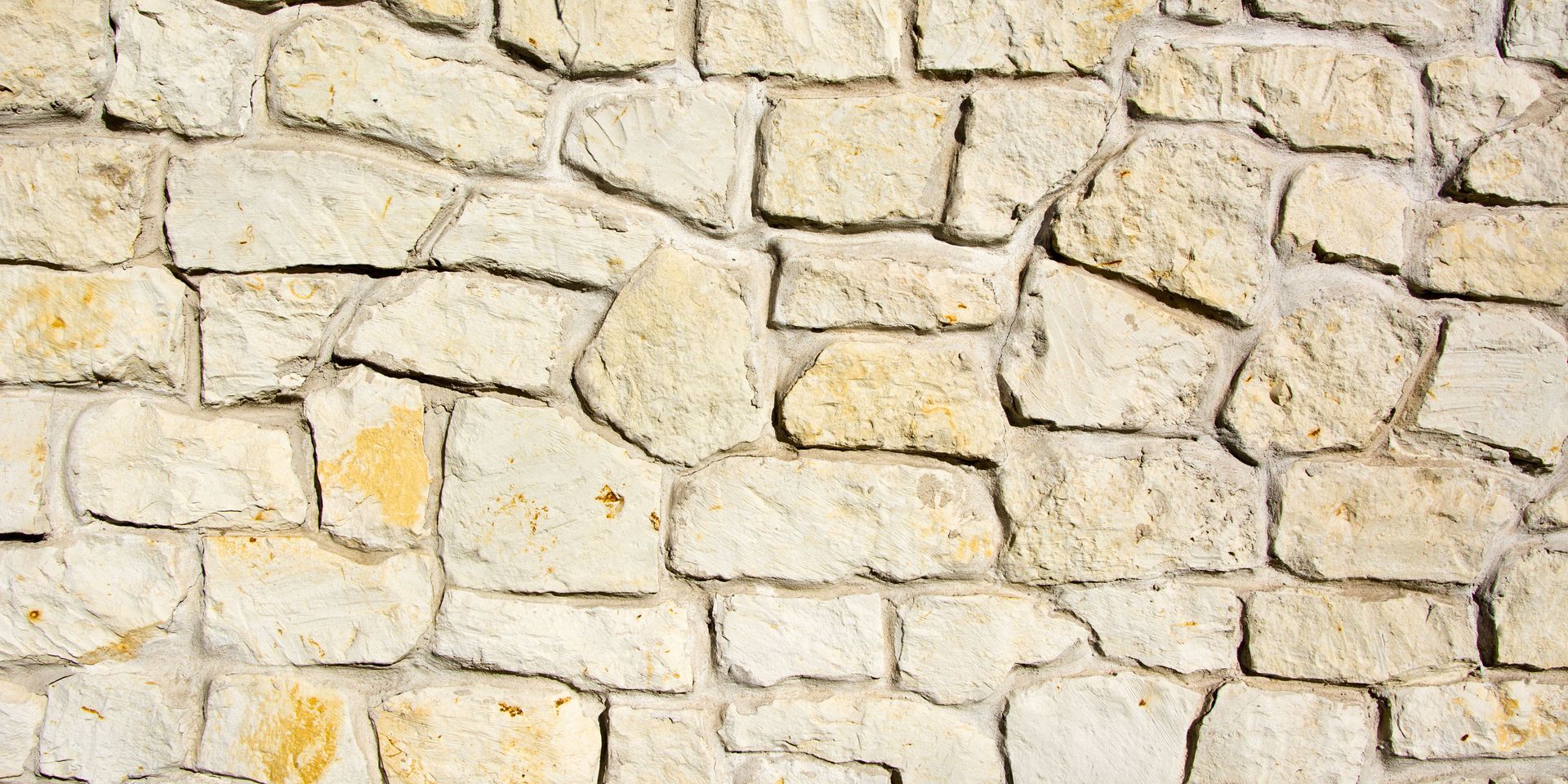 Close-up of a light-colored stone wall with irregular shaped blocks and visible mortar.