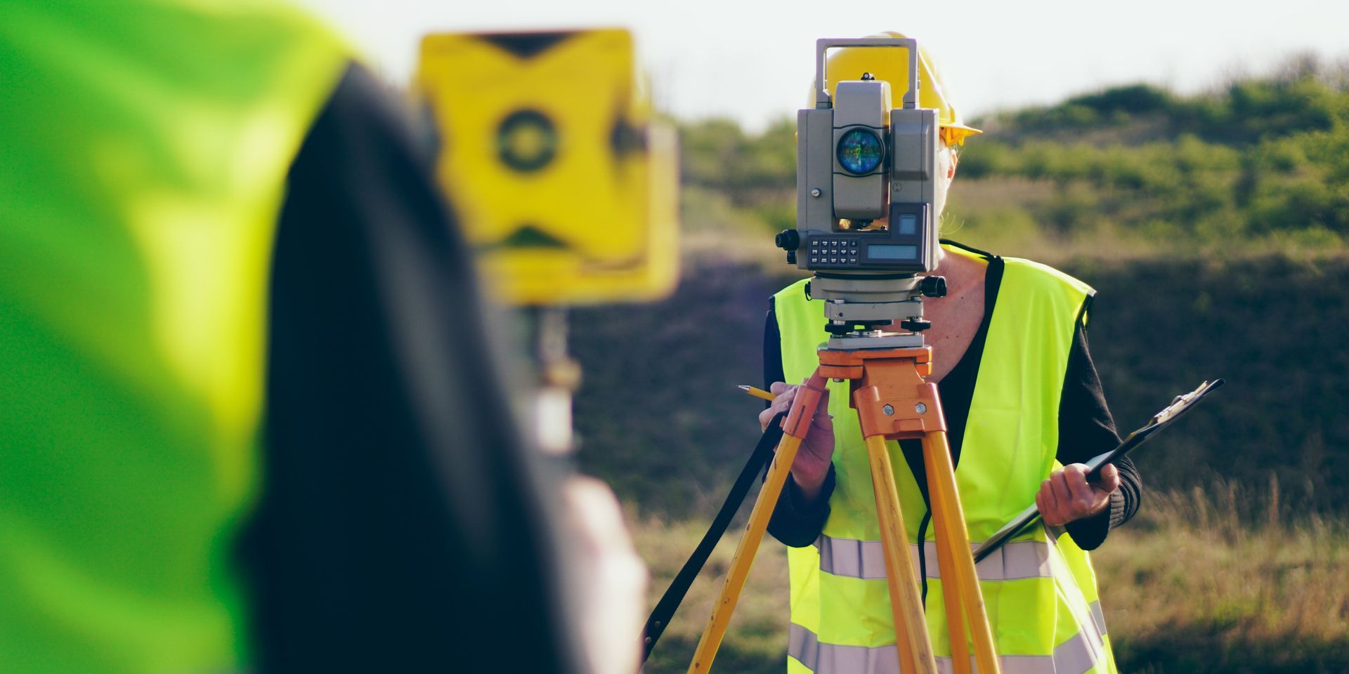 A woman is using a theodolite to measure a field.