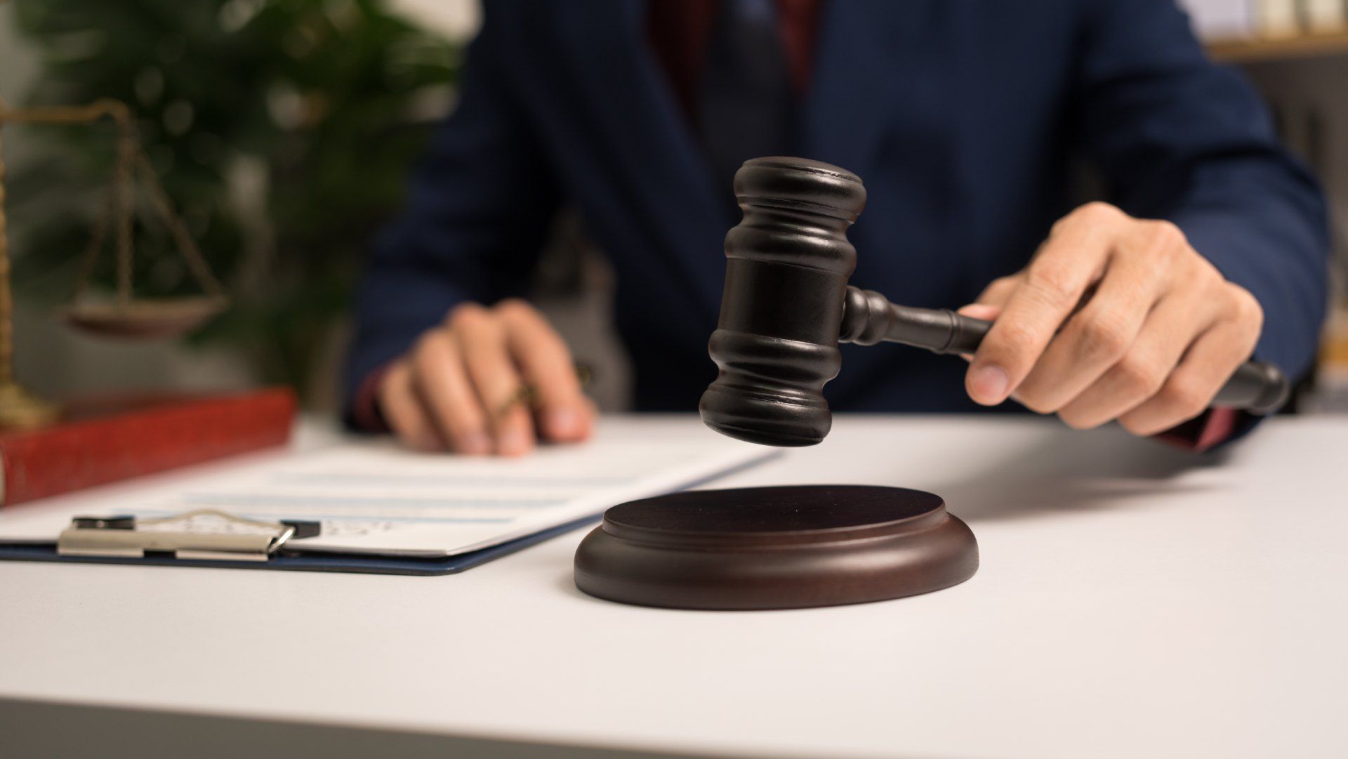 A judge is sitting at a table holding a wooden gavel.