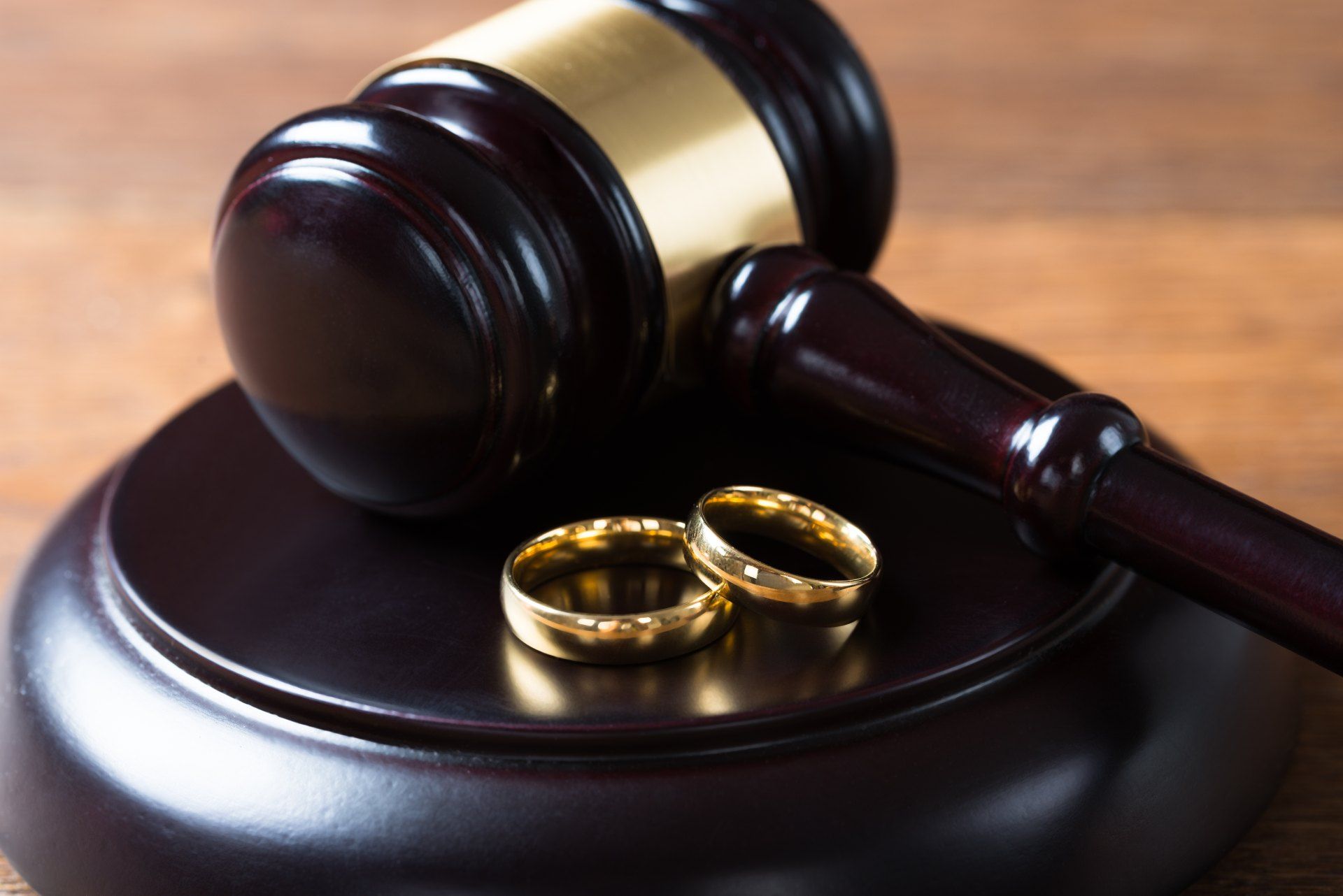 A couple of wedding rings are sitting on top of a wooden judge 's gavel.