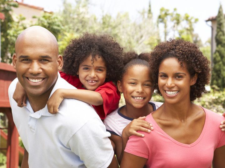 A family is posing for a picture together and smiling for the camera.