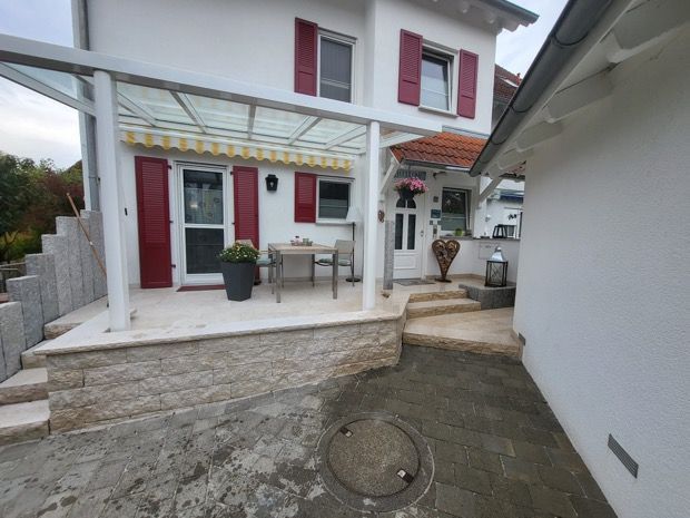 Ein grünes Rohr liegt im Dreck neben einem Haus