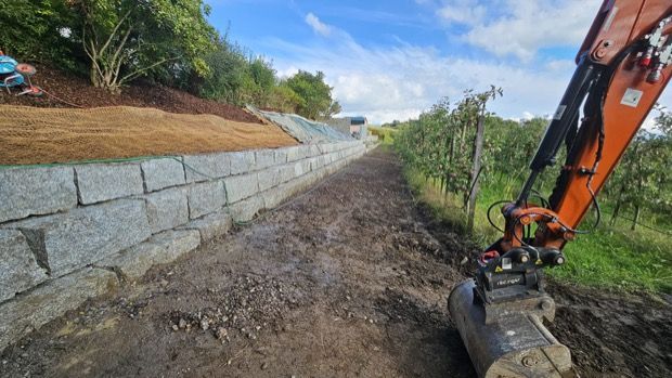 Vor einem im Bau befindlichen Gebäude liegt ein großer Erdhaufen.