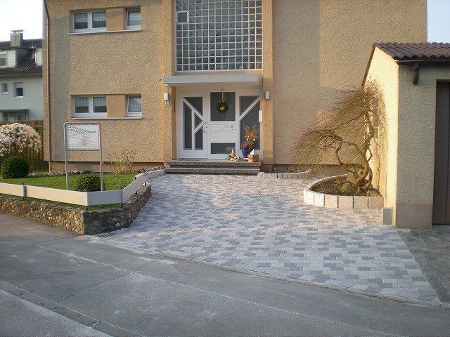 Ein Haus mit einer gepflasterten Auffahrt, die zur Haustür führt