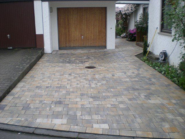 Eine gemauerte Auffahrt, die zu einer Garage mit einem Holztor führt