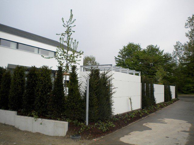 Ein weißer Zaun ist von Bäumen und Büschen umgeben