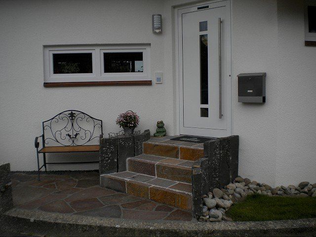 Ein weißes Haus mit Treppe und einer Bank davor